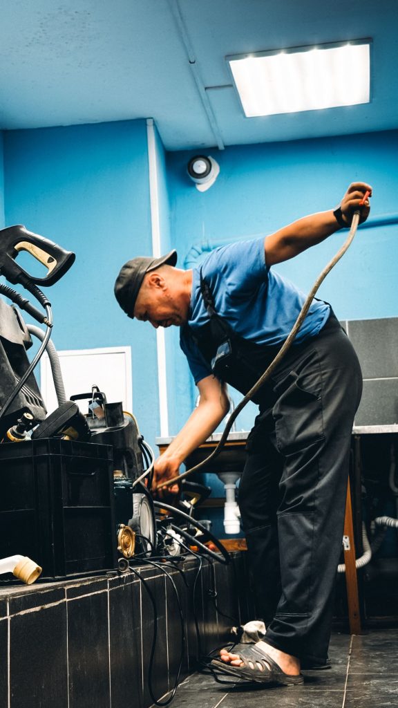 Drain technician feeding a motorised cable machine into a floor drain