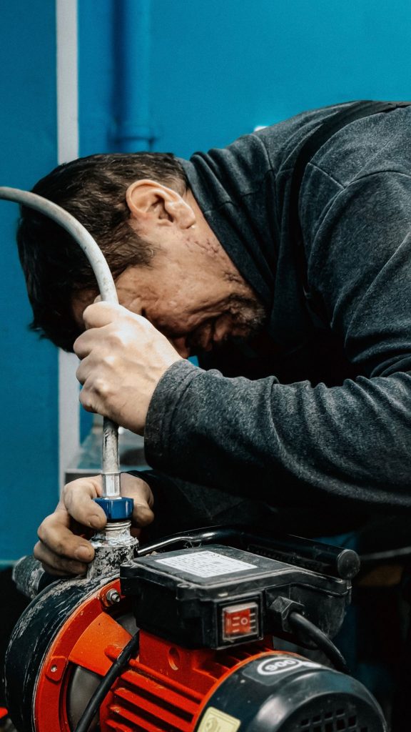 Technician clearing a blocked drain with a hand cable