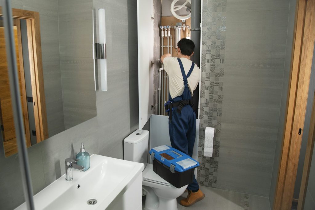 Technician repairing plumbing in a bathroom