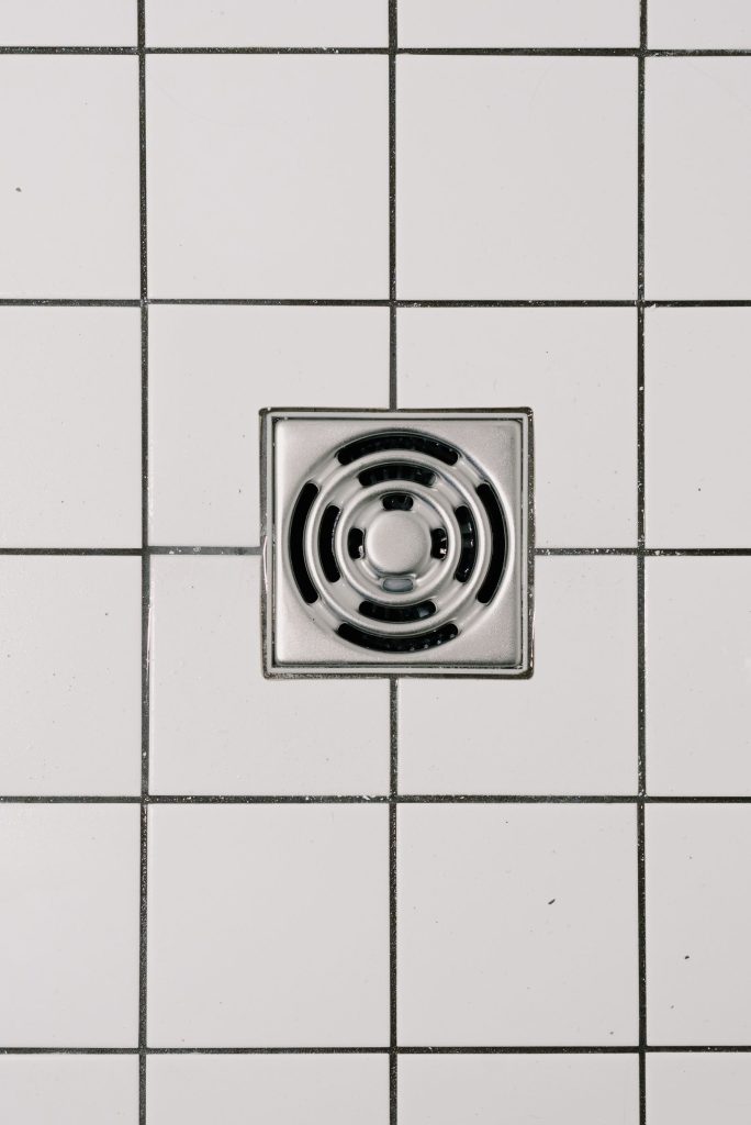 Square stainless shower drain in white tiles