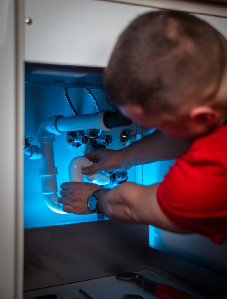 Technician removing the trap in a sink cabinet