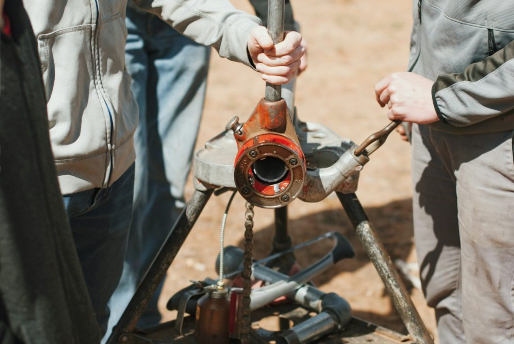 Two technicians working on a pipe with a wrench