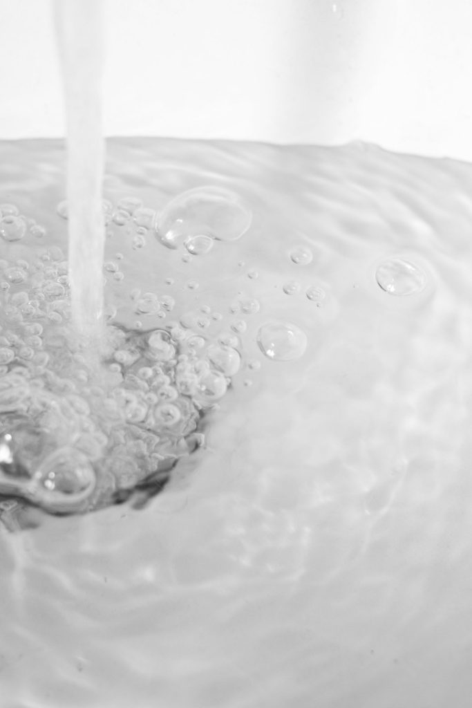 Water with bubbles flowing into a kitchen sink